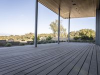 the covered deck area with the view to the outdoors area of the house and forest in the distance