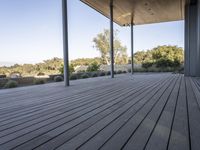 the covered deck area with the view to the outdoors area of the house and forest in the distance