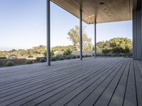 the covered deck area with the view to the outdoors area of the house and forest in the distance