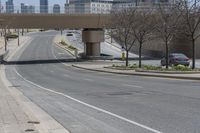 a empty road with a sidewalk and street lights on top of it in the city