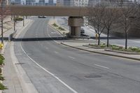 a empty road with a sidewalk and street lights on top of it in the city