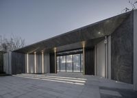 the building is made up of glass and concrete, and has a wide terrace and large entrance