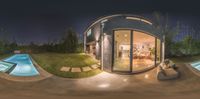 a small round building with glass doors at night with a swimming pool visible in the middle