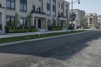 a lone person rides a bike down the road between two row homes and green grass