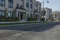 a lone person rides a bike down the road between two row homes and green grass