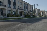 a lone person rides a bike down the road between two row homes and green grass