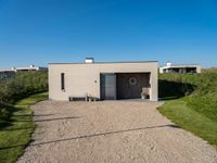 a small building that is made from concrete and a grass covered ground that looks like gravel with a sign near by