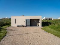 a small building that is made from concrete and a grass covered ground that looks like gravel with a sign near by