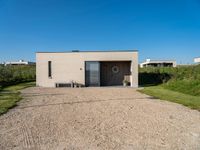 a small building that is made from concrete and a grass covered ground that looks like gravel with a sign near by