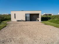 a small building that is made from concrete and a grass covered ground that looks like gravel with a sign near by