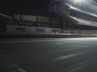 an empty tennis court with lights shining on the side of it at night in a stadium