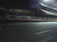 an empty tennis court with lights shining on the side of it at night in a stadium