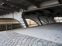 an overpass bridge with a sidewalk underneath it and a red fire hydrant next to it
