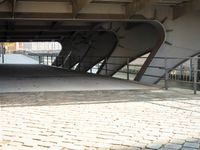 an overpass bridge with a sidewalk underneath it and a red fire hydrant next to it