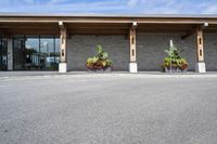 a stone building on the left side with a sidewalk to right and a parking lot area in front