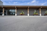 a stone building on the left side with a sidewalk to right and a parking lot area in front