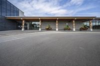 a stone building on the left side with a sidewalk to right and a parking lot area in front