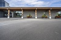 a stone building on the left side with a sidewalk to right and a parking lot area in front