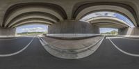 a fisheye lens photograph of a modern street with arches and arches and a paved roadway in the background