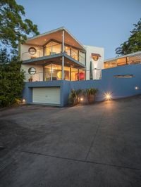 a modern style home with two story exterior with outdoor lighting on and landscaping in the foreground