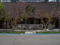 street corner with tree on the corner of the corner and a building behind it that is surrounded by multiple windows and a perforated brown lattice