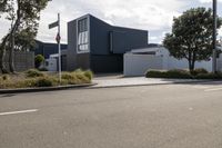 a grey house on a grey background with trees and bushes and plants, and a small fence