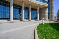 a tall building with a lot of windows sitting outside it on some green grass in front of some stone pillars