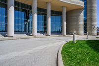 a tall building with a lot of windows sitting outside it on some green grass in front of some stone pillars