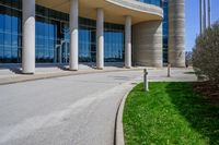 a tall building with a lot of windows sitting outside it on some green grass in front of some stone pillars