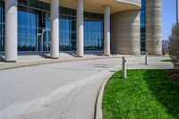 a tall building with a lot of windows sitting outside it on some green grass in front of some stone pillars