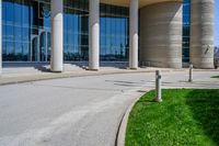 a tall building with a lot of windows sitting outside it on some green grass in front of some stone pillars