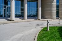 a tall building with a lot of windows sitting outside it on some green grass in front of some stone pillars