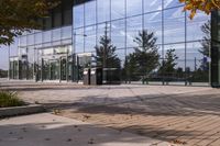 a walkway in front of an office building with some trees in the foreground, and fall foliage all around it