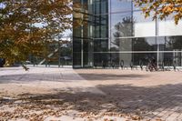 a walkway in front of an office building with some trees in the foreground, and fall foliage all around it