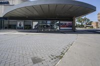 a person sitting at the bench in front of a mall that is empty of people