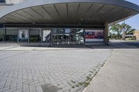 a person sitting at the bench in front of a mall that is empty of people