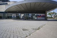 a person sitting at the bench in front of a mall that is empty of people