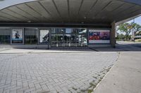 a person sitting at the bench in front of a mall that is empty of people