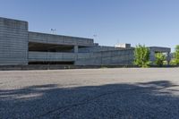 a city building with some concrete walls and a few bushes in front of it near an empty parking lot