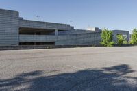 a city building with some concrete walls and a few bushes in front of it near an empty parking lot