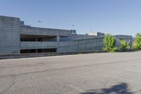 a city building with some concrete walls and a few bushes in front of it near an empty parking lot