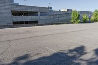 a city building with some concrete walls and a few bushes in front of it near an empty parking lot