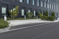 a parked car on a paved street in front of black buildings and a parking space