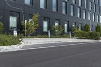 a parked car on a paved street in front of black buildings and a parking space