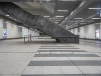 people waiting at a train station with stairs in the middle of the room, and empty