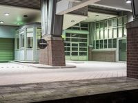 train station platform with green doors and train car on either side of train tracks and a clock on the outside of the platform