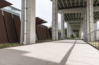 an empty sidewalk with a long metal fence near the stairs to a building in the background