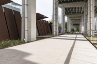 an empty sidewalk with a long metal fence near the stairs to a building in the background