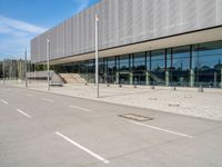 an empty lot with a building, bus stop and traffic cones in the street nearby