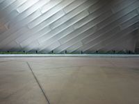 the front side of a large modern building with metallic siding and a light shining on it